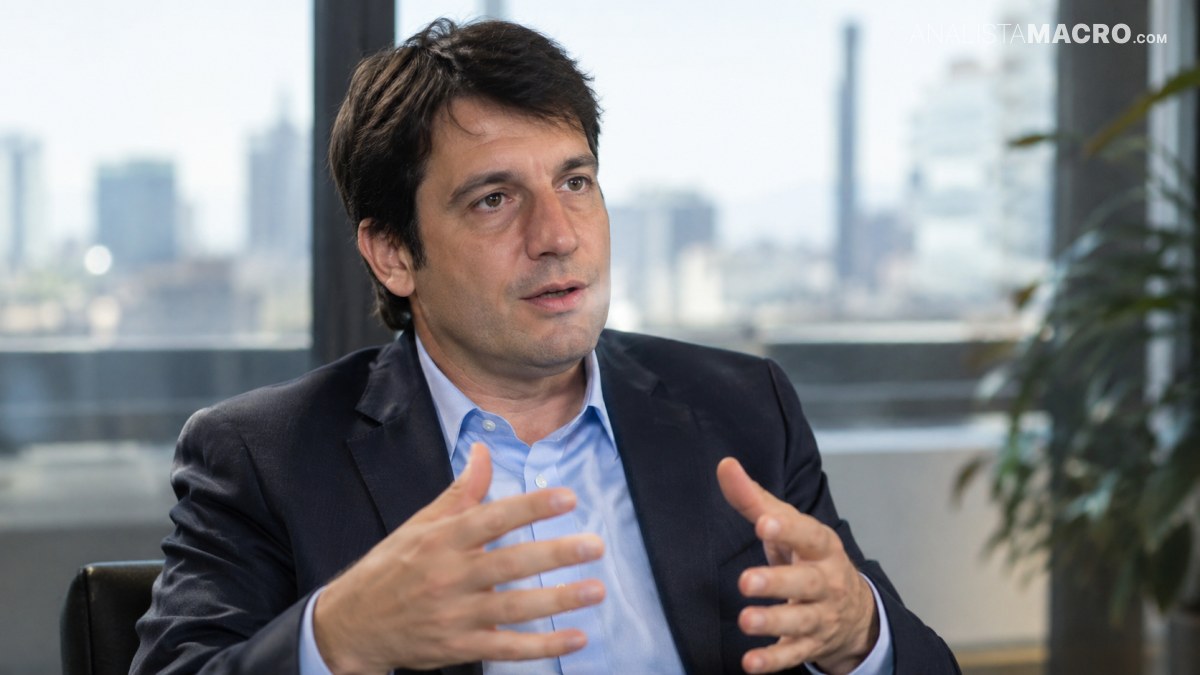 Hombre de cabello oscuro, con traje y camisa azul, gesticula mientras habla sentado frente a una ventana.