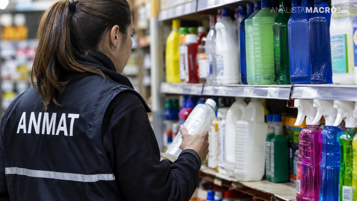 Una mujer con chaleco que dice ANMAT sostiene un envase mientras observa productos de limpieza en estanterías.