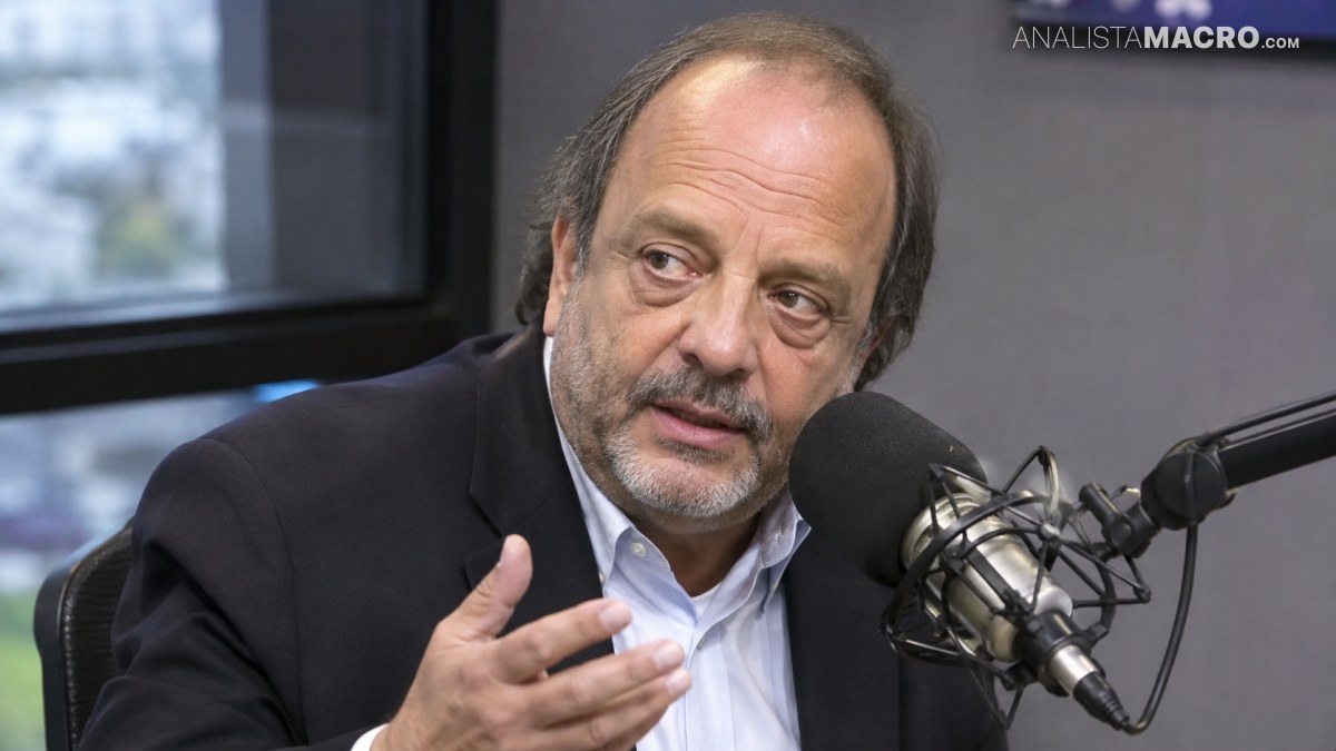 Hombre con traje oscuro habla en un estudio frente a un micrófono con brazo, mirando a cámara.