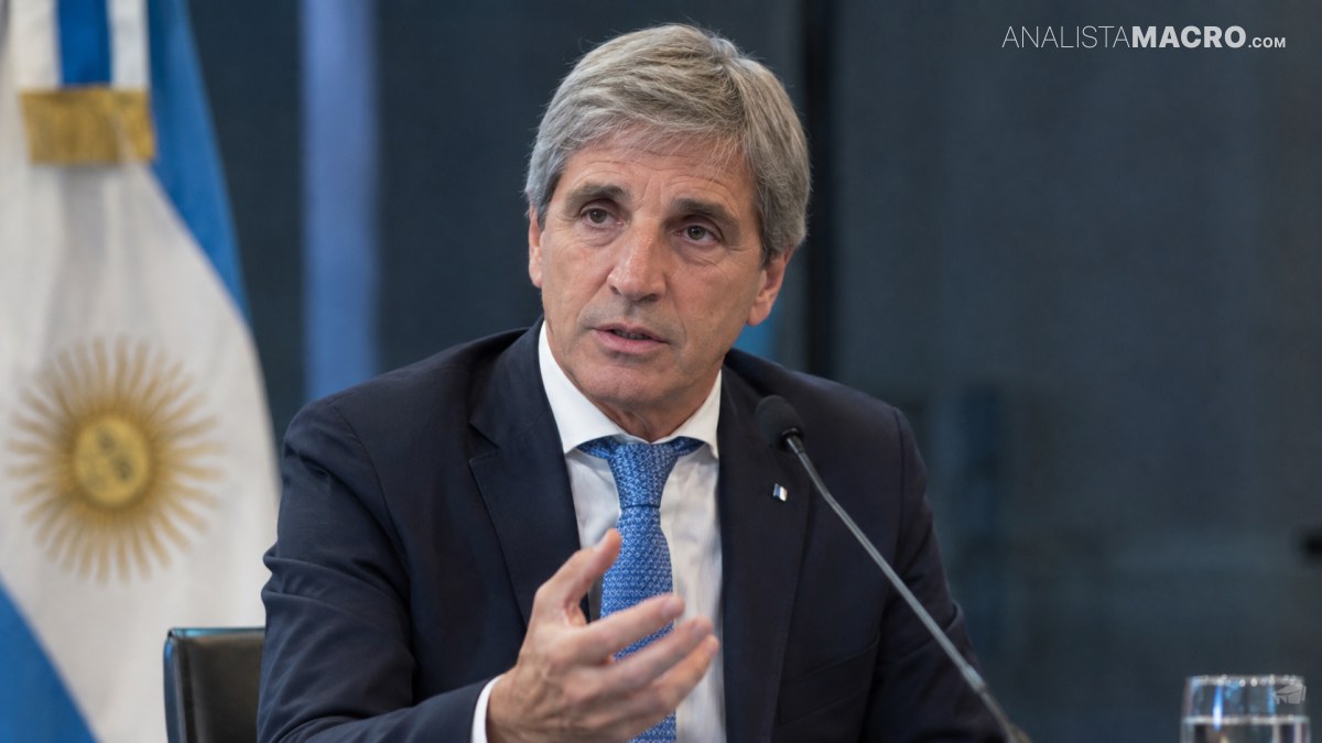 Hombre de cabello gris, con traje oscuro y corbata azul, habla ante un micrófono mientras gesticula con una mano.