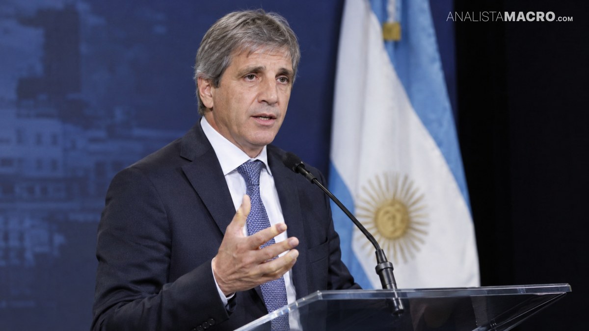 Hombre de traje y corbata habla ante un micrófono, gesticulando con una mano, frente a una bandera argentina.