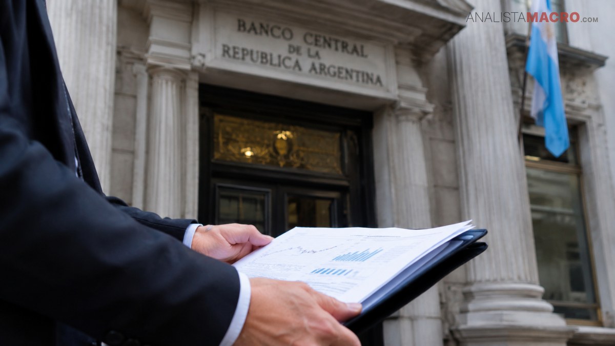 Persona con traje sostiene una carpeta con gráficos frente a la entrada del Banco Central de la República Argentina.
