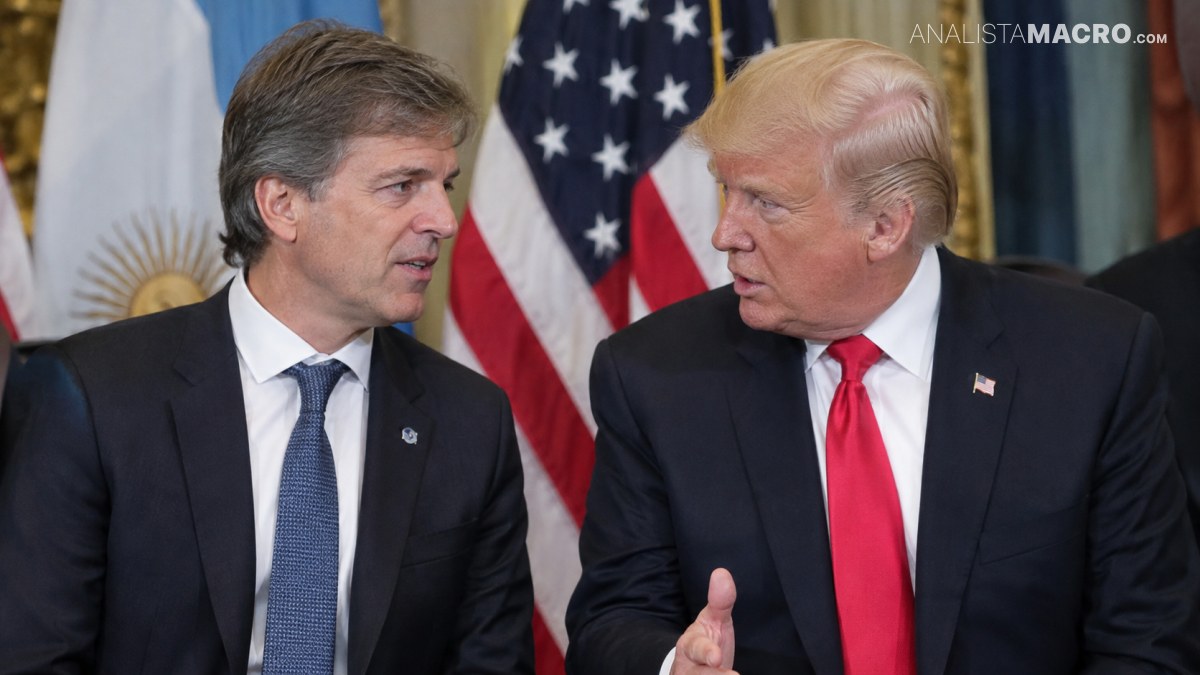 Dos hombres con traje conversan frente a las banderas de Estados Unidos y Argentina.