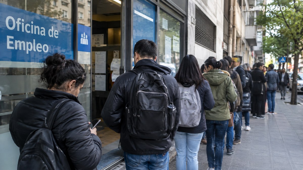 Personas hacen fila frente a una oficina de empleo, mientras otras esperan en la acera junto a la entrada.