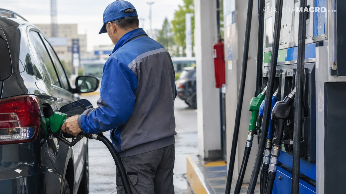 Un empleado con uniforme azul y gris reposta combustible en un automóvil junto a un surtidor.