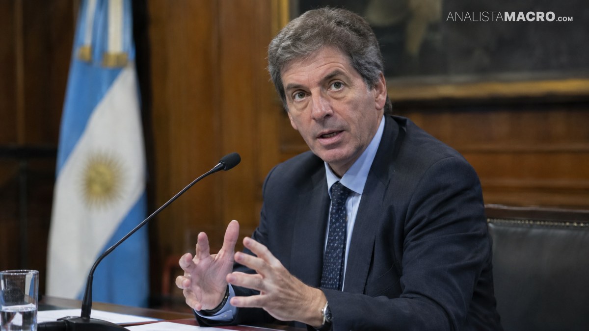 Hombre de traje oscuro habla ante un micrófono, con las manos gesticulando, mientras una bandera argentina aparece al fondo.