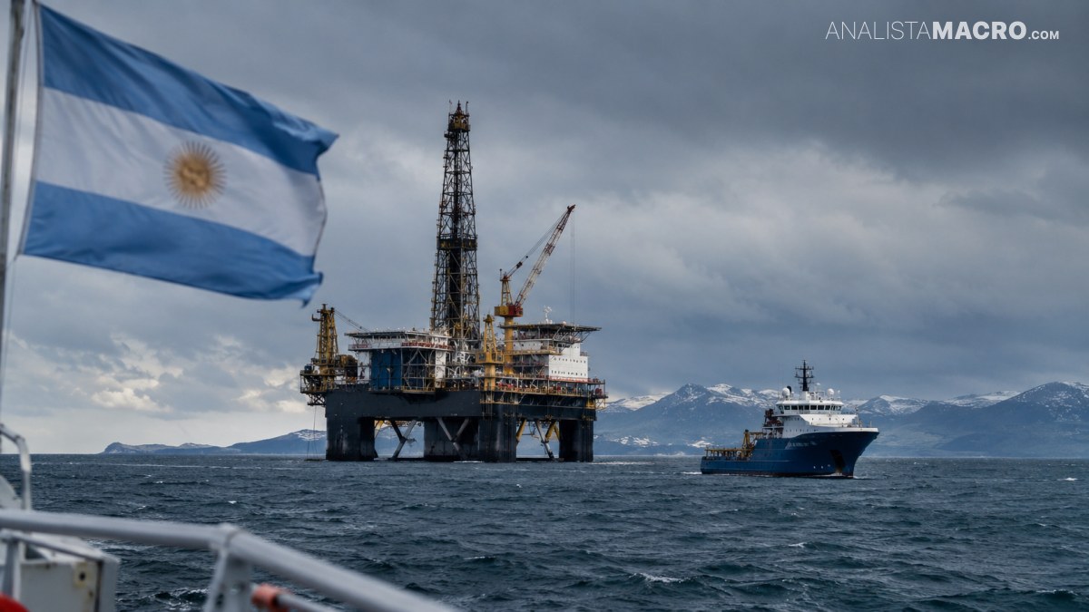 Plataforma petrolera y barco en el mar, con una bandera argentina ondeando bajo un cielo nublado y montañas al fondo.