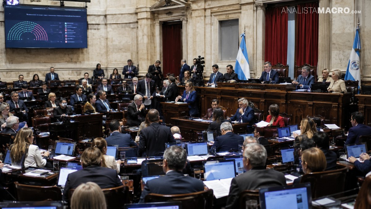 Congreso con numerosas personas sentadas en bancas, pantallas con gráficos, banderas y un estrado con panelistas.