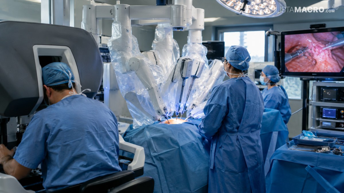 Personal médico realiza una cirugía asistida por robot mientras observa imágenes endoscópicas en una pantalla.