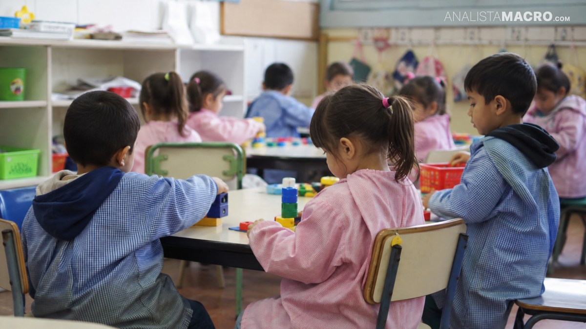 Niños sentados alrededor de mesas en un aula, realizando actividades con bloques y otros materiales.