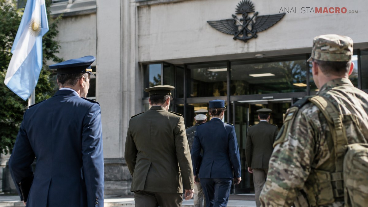 Varios militares de pie frente a un edificio con bandera argentina y un emblema en la fachada.