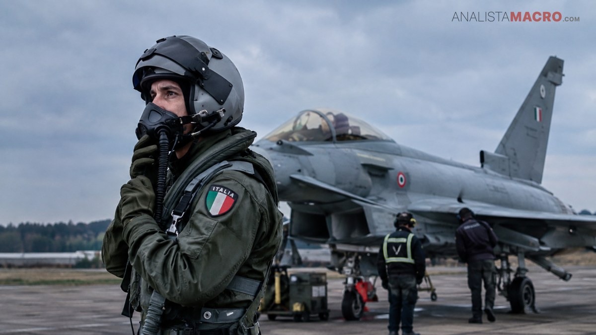 Piloto con casco y máscara sostiene un equipo de respiración frente a un avión militar estacionado.