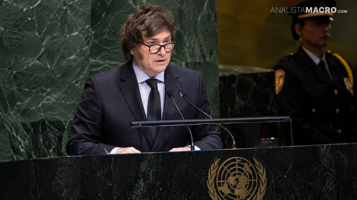 Un hombre con gafas y traje oscuro habla detrás de un atril con micrófonos y emblema de la ONU.